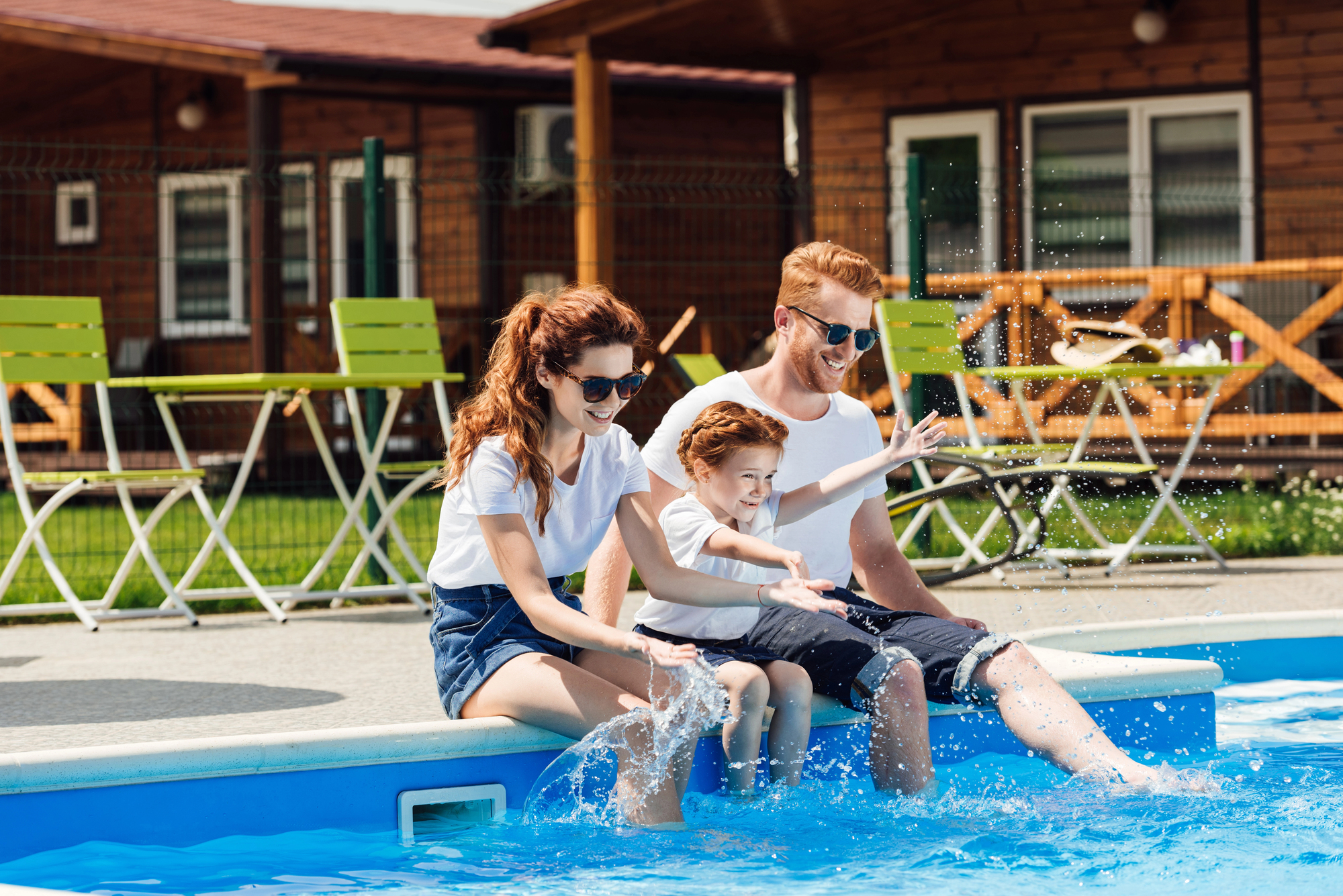 Family Enjoying the Pool Young parents with an adolescent boy site poolside with their feet in the water
